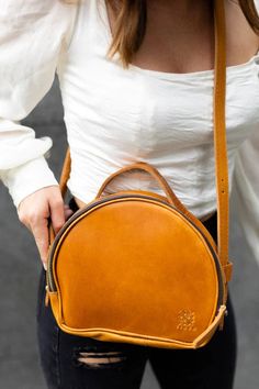 The Elsa round crossbody bag is a light and stylish bag that's just the right size for all your adventures! This round crossbody bag is crafted of genuine premium Ethiopian leather with an adjustable strap for the perfect fit. Wear this round handbag as a crossbody or shoulder bag. Plus the interior pockets keep accessories organized. This round crossbody bag measures 9" L x 3" W x 8" H Round Leather Handbag Features: Crossbody bag crafted from premium Ethiopian leather Premium brass exterior zi Round Brown Shoulder Bag For Travel, Brown Round Shoulder Bag For Travel, Round Shoulder Bag For Travel, Everyday Leather Shoulder Bag With Round Case, Round Leather Shoulder Bag For Everyday Use, Brown Round Case Shoulder Bag, Round Case Shoulder Bag With Adjustable Strap For Travel, Round Handbag, Round Crossbody Bag