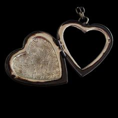 two silver heart shaped lockes sitting next to each other on a black background,