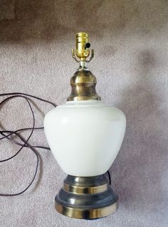 a white glass lamp sitting on top of a table next to a wall charger