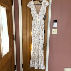 a white dress hanging on a door in front of a pink wall and wooden door