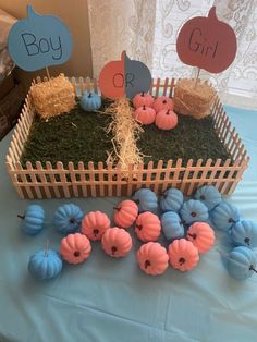 a table topped with fake pumpkins and hay in front of a wooden box filled with grass