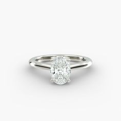 an oval shaped diamond engagement ring on a white background with the center stone set in 18k white gold