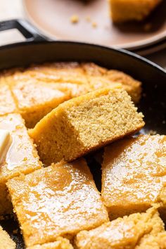 pieces of cake in a skillet with butter on top and one piece being cut into squares