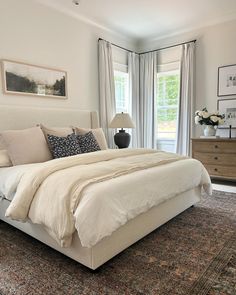 a large bed sitting in the middle of a bedroom next to a dresser and window