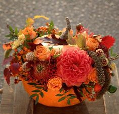 an orange pumpkin decorated with flowers and foliage