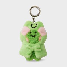 a green stuffed animal keychain with a smiling face on it's chest