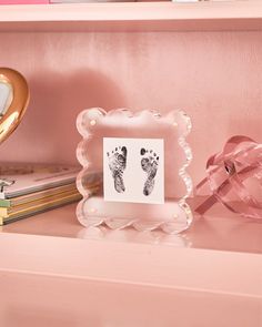 a baby's foot print is placed on top of a pink shelf