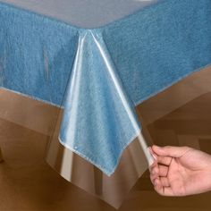 a person is holding the edge of a blue table cloth with silver foil on it