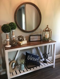 a white console table with a mirror and vases on it, along with other decorative items