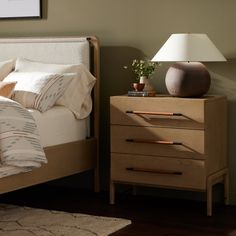 a bedroom scene with focus on the bed and nightstand, which has a lamp next to it