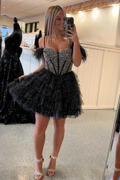 This homecoming dress, with its cold shoulder design accented by delicate feathers, is perfect for a night of dancing. The beaded top adds a touch of glamour while the tiered a-line skirt provides a flattering silhouette. Turn heads and feel confident in this glittery black dress. ♡ SKU: FV12894 ♡ Fabric: Tulle ♡ Silhouette: A-Line ♡ Back Style: Zipper ♡ Embellishment: Ruffles, Feathers ♡ Length: Above Knee ♡ Fully lined & Built with bra ♡ Size: US 2-16. True to the size chart. Check our Size Ch Fitted Feather Dresses For Homecoming, Party Dresses With Feathers And Tulle, Party Dresses With Feathers And Tulle Material, Tulle Party Dress With Feathers, Feather Trim Dresses For Homecoming And Prom Season, Feather Trim Dress For Homecoming And Prom, Feather Trim Dress For Homecoming And Prom Season, Feathered Evening Dress For Prom, Feathered Evening Dress For Prom Season