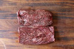 two pieces of beef sitting on top of a wooden table