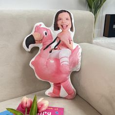 a pink flamingo pillow sitting on top of a white couch