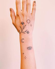 a woman's hand with an eye and flower tattoo on her left wrist,