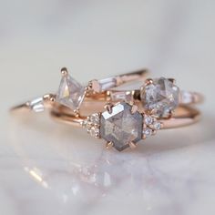 two gold rings with white diamonds on them sitting on top of a marble countertop