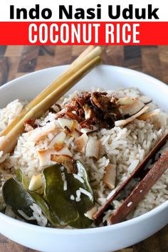 a bowl filled with rice and vegetables on top of a wooden table next to chopsticks