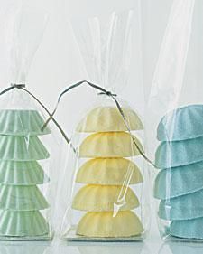 three different colored seashells wrapped in plastic bags on a white surface with string