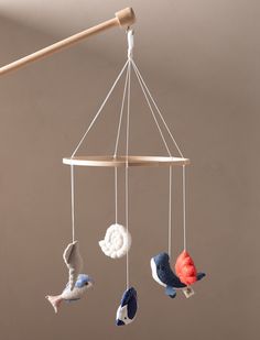 three birds are hanging from a wooden rod and some yarn is attached to the strings