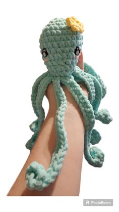 a crocheted octopus stuffed animal is held in someone's hand with its arm