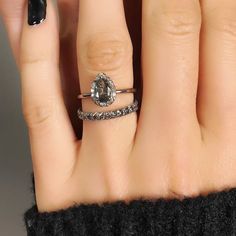 a woman's hand with two rings on her fingers and one ring in the middle