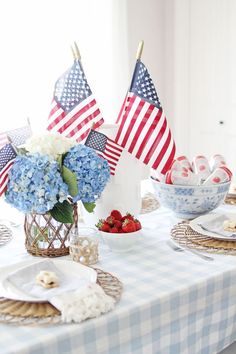 the table is set with blue and white plates, silverware, and american flags