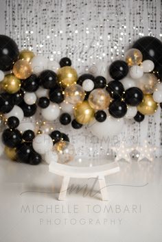 black, white and gold balloons in front of a backdrop