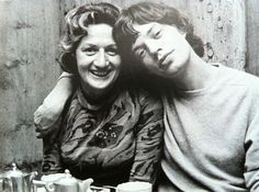 an old photo of two people sitting at a table with cups and saucers in front of them