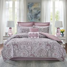 the comforter is made up with pink and grey paisley designs on it, along with two lamps