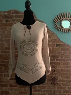 Vintage '90 long sleeve t-shirt made in Italy. Beautiful beige cotton blouse with ethnic sparkling printed mandalas. Cross ties closure. Pointed mandala decorated sleeves. Pointed font cut. Used in perfect condition Measurements: Fits M international Size on tag: M Colour: Brown / Beige Actual measurements when laid flat: Back: 33cm Chest: 46 cm Waist: 34 cm Length: 47-55 cm (pointed part) *All measurements such as chest, waist or hips are taken with the item flat and are doubled for circumferen Bohemian Fitted Cotton Tops, Bohemian Cotton Tops For Fall, Fitted Cotton Bohemian Tops, Fitted Bohemian Cotton Tops, Fall Bohemian Cotton Tops, Bohemian Fitted Crew Neck Top, Fitted Bohemian Crew Neck Top, Casual Beige Blouse For Festival, Bohemian Tunic Tops For Fall