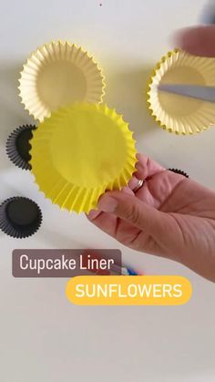 cupcake liner sunflowers are being held by someone