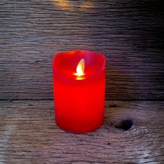 a red candle sitting on top of a wooden table