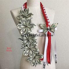 a white mannequin wearing a red and white ribbon with money attached to it