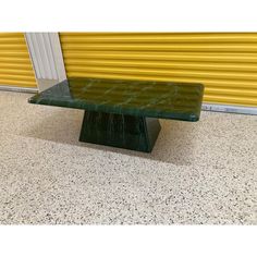 a green marble table sitting in front of a yellow door