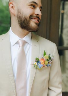 a man in a suit and tie with flowers on his boutonniere is smiling