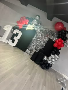 the room is decorated with black, silver and red balloons for an 13th birthday party