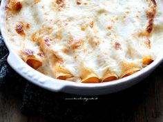 a casserole dish with cheese and sauce in it sitting on a table top