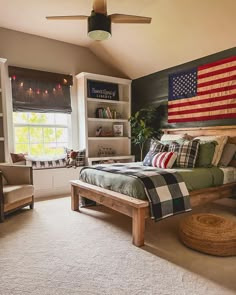 a bed room with a neatly made bed and an american flag on the wall