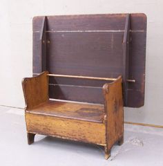 an old wooden bench sitting in front of a wall with a coat rack on it