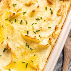 a casserole dish filled with potatoes and topped with green onion sprinkles