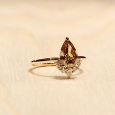 a yellow diamond ring sitting on top of a wooden table