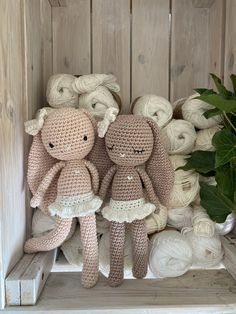 two crocheted stuffed animals sitting next to each other on a shelf with balls of yarn