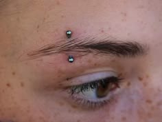 a close up of a person's eye with small piercings on their forehead