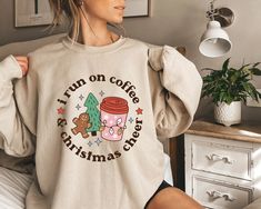 "I Run On Coffee And Christmas Cheer Sweatshirt, Retro Christmas Coffee Drinks Crewneck, Coffee Latte Xmas Tee Shirt, Coffee Lover Unisex Crewneck Sweatshirt. Loose fit for a comfortable feel. FABRICATION * 50% cotton, 50% polyester * Runs true to size SIZING This style is a Unisex Sweatshirt. If you are unsure about the size and the color you should order, please refer to the size and color chart in the pictures. CARE INSTRUCTIONS * Machine wash: warm (max 40C or 105F) * Tumble dry: low heat * Book Tree, Retro Sweatshirts, Christmas Tree Shirt, Gifts For Librarians, Merry Christmas Shirts, Tree Shirt, Sweatshirt Christmas, Coffee Latte, Christmas Hoodies