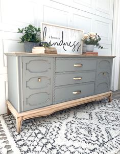 a gray dresser sitting on top of a rug in front of a white door with a sign above it