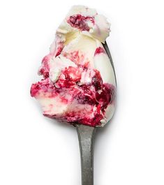 a scoop of ice cream with raspberry sauce on it is sitting on a spoon