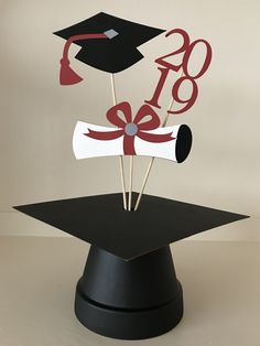 graduation cake topper in the shape of a mortar and diploma cap with red ribbon