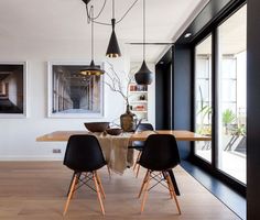 the dining room table is surrounded by black chairs and artwork on the wall behind it