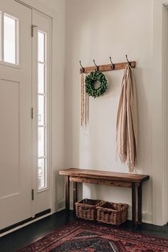 a wooden bench sitting in front of a door with a wreath hanging on the wall