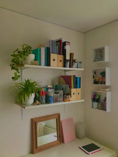 a white desk topped with lots of books next to a wall mounted shelf filled with office supplies