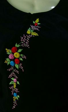 a woman's black top with colorful flowers and leaves embroidered on the neckline